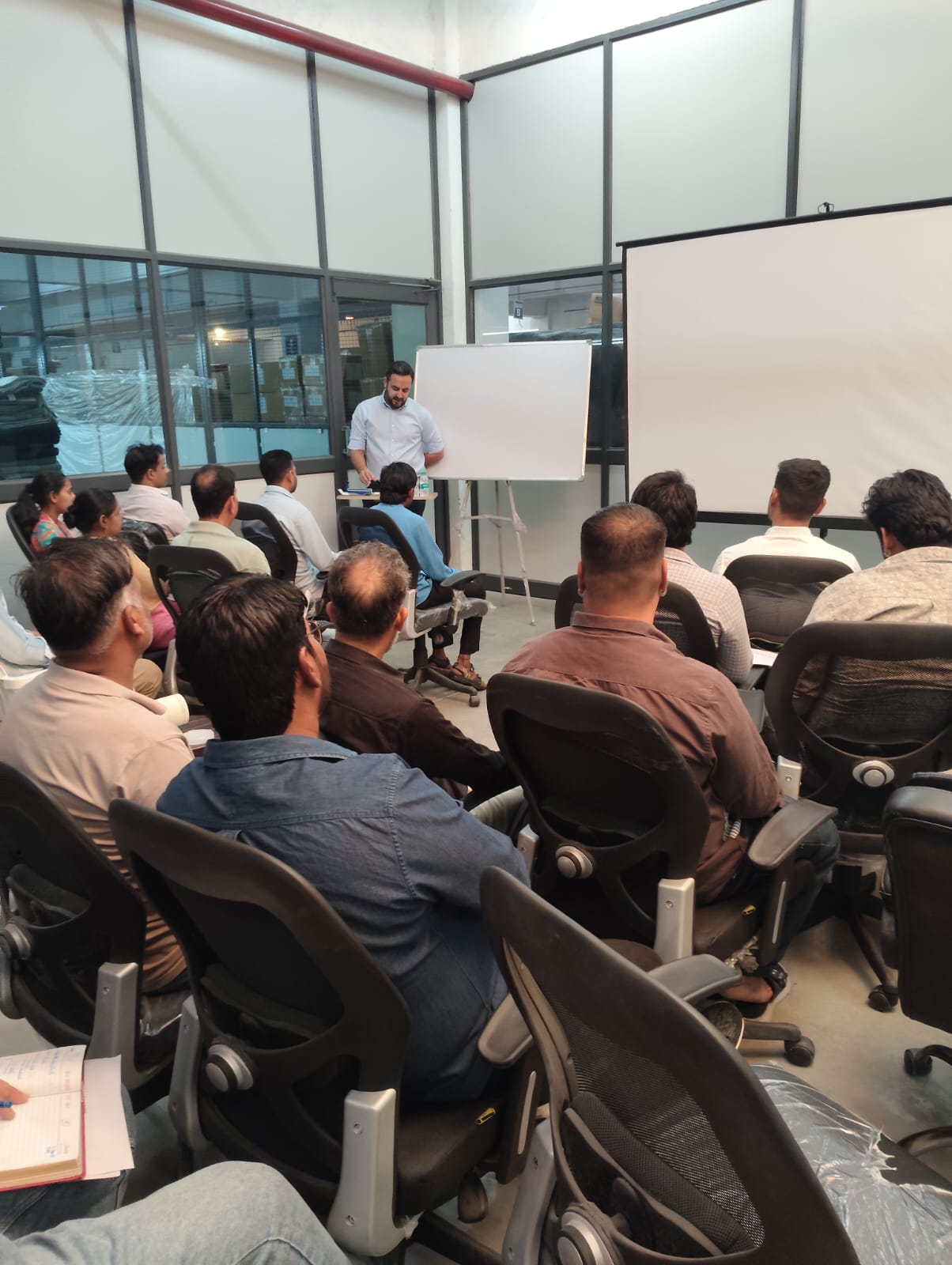 Staff seated in a classroom session as a trainer presents at a whiteboard