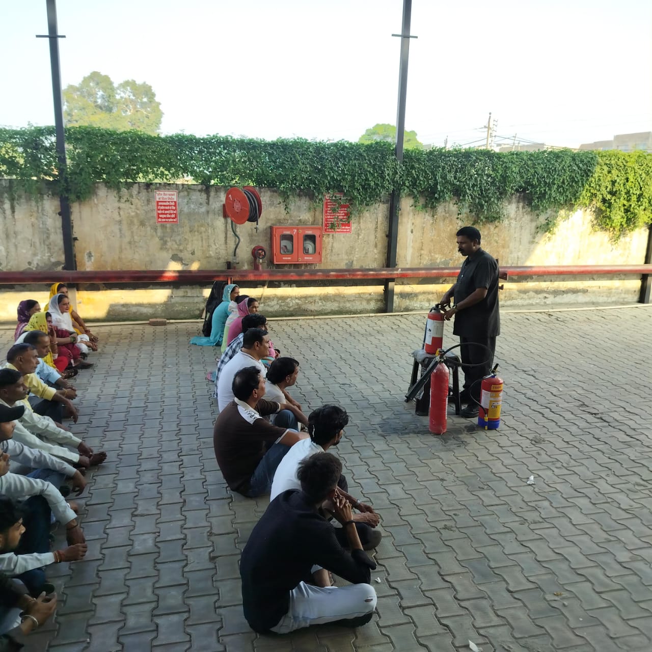 Safety officer demonstrating fire extinguishers to seated staff