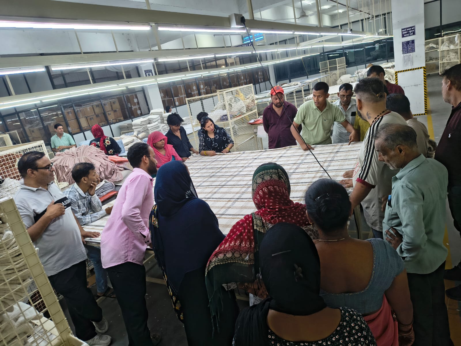Workers gathered around a large checked throw laid out for inspection