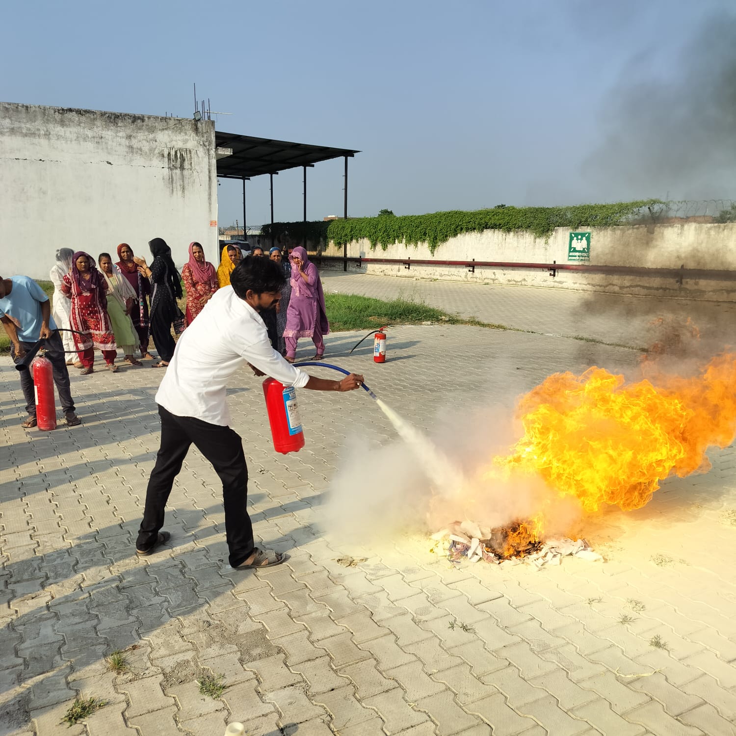 Employee putting out a live fire with an extinguisher during a fire drill