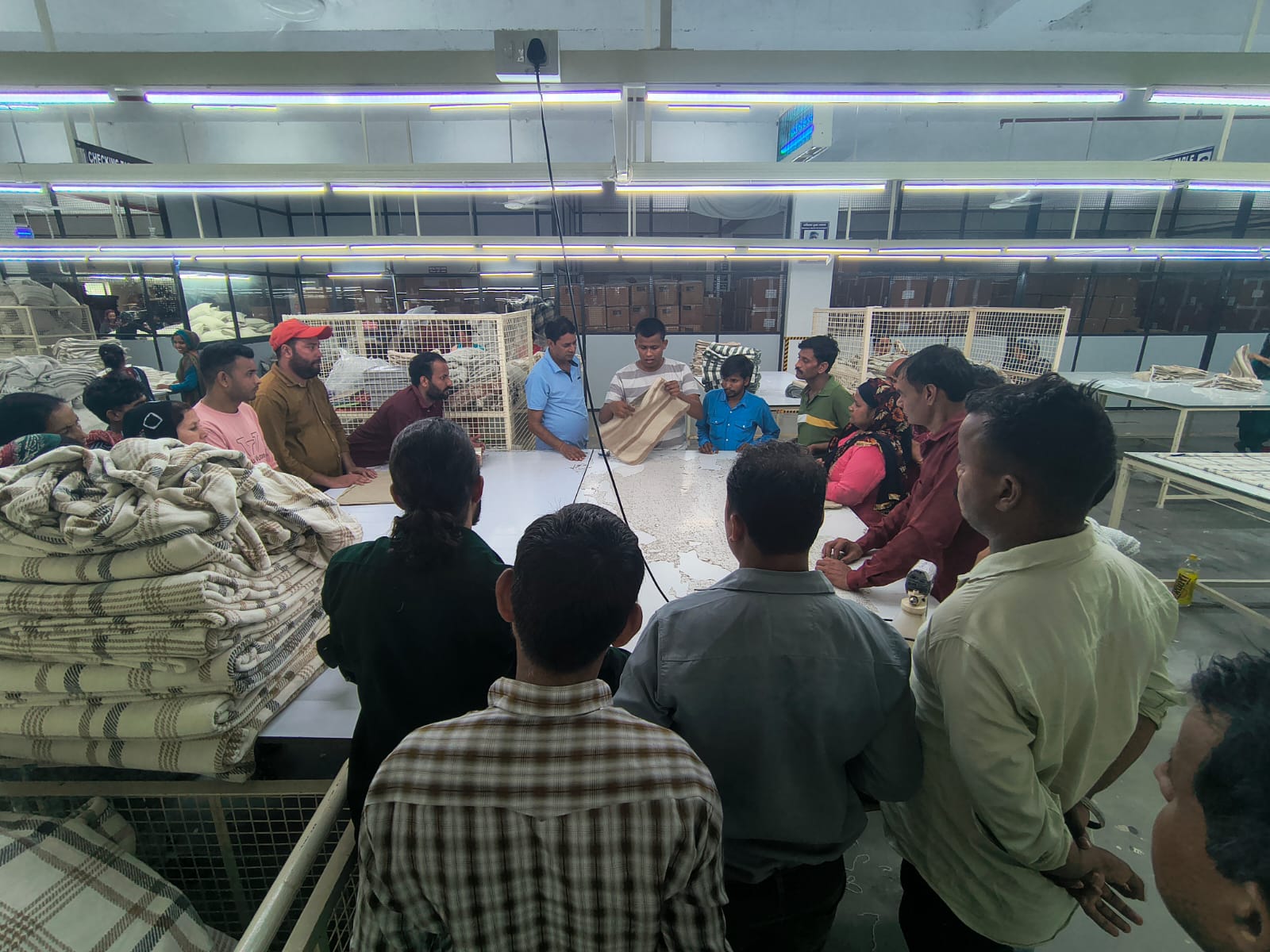 Trainer explaining stitching standards to a group on the production floor