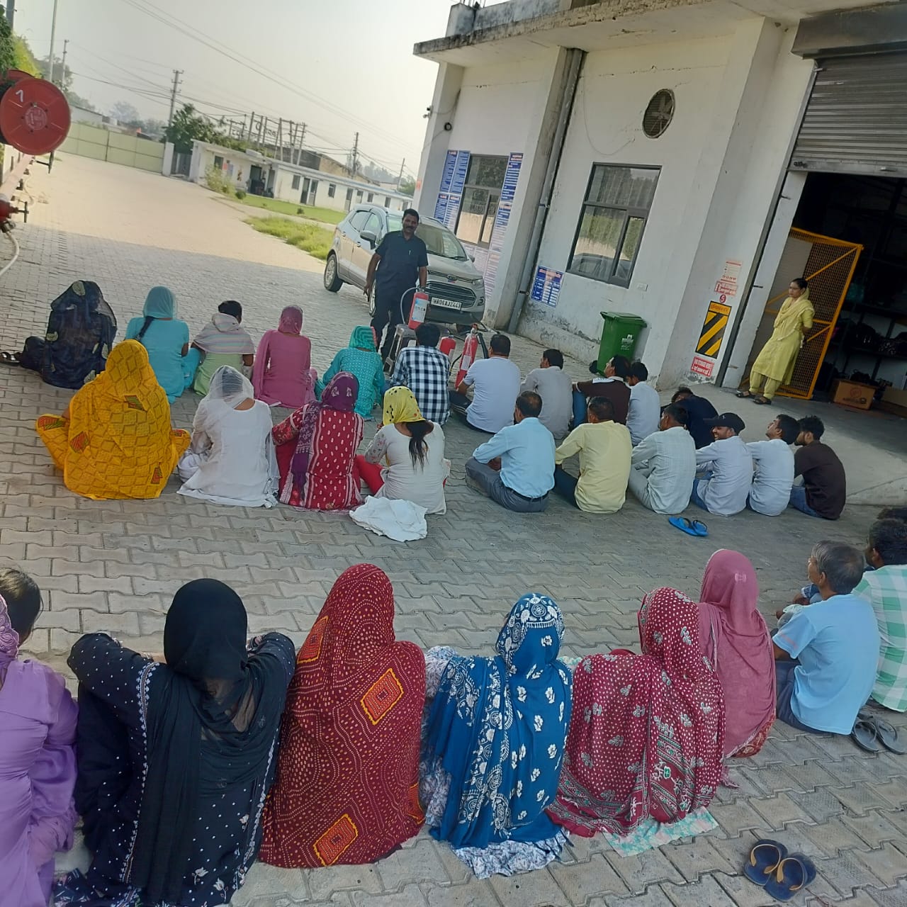 Staff seated outside the facility for a fire safety briefing